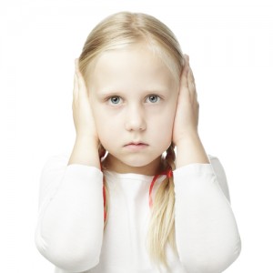 A little blonde girl with both of her hands over her ears isolated on white background