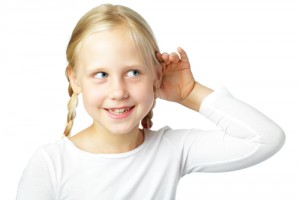 A little blonde girl with one hand cupped to her ear isolated on a white background
